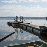 Peaceful view of a lakeside pier on a sunny day with calm water reflections.