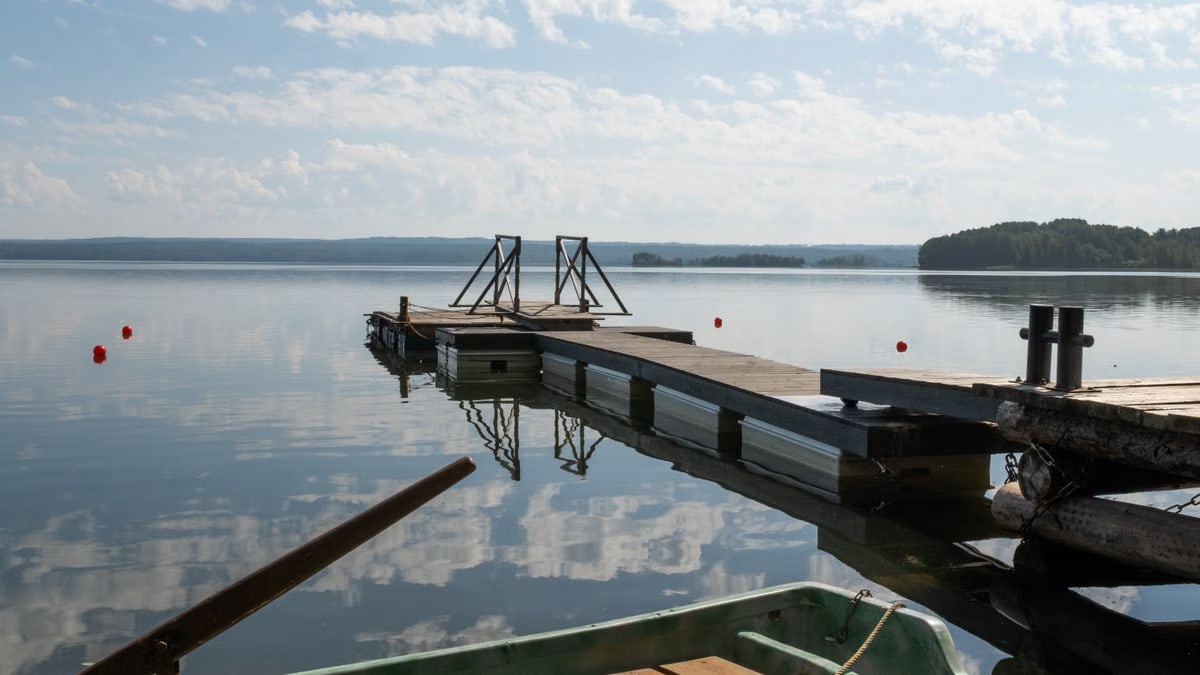 Peaceful view of a lakeside pier on a sunny day with calm water reflections.